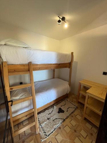 a bedroom with two bunk beds and a table at Single fin beach house in Taghazout
