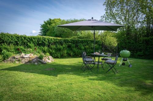 a table and chairs under an umbrella in a yard at The Snickett in Combe Martin