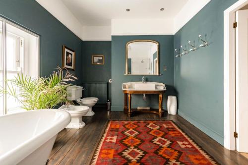 een badkamer met een bad, een wastafel en een spiegel bij Wellington House - Norfolk Holiday Properties in Lowestoft