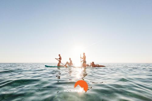 a group of people on a surfboard in the water at #056 Old Post Office by Home Holidays in Albufeira