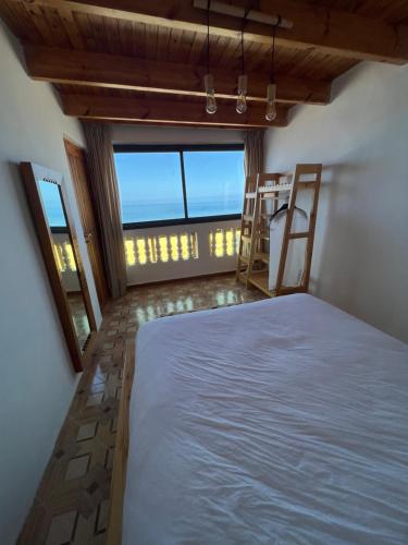 a bedroom with a bed and a large window at Single fin beach house in Taghazout