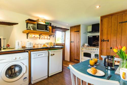 a kitchen with a table and a stove and a dishwasher at The Snickett in Combe Martin