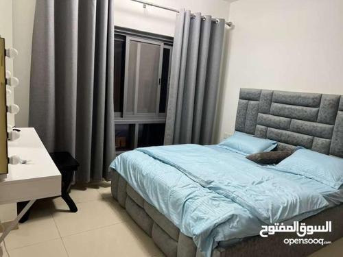 Schlafzimmer mit einem Bett mit blauer Bettwäsche und einem Fenster in der Unterkunft One Bed Room Apartment Muscat Hills in Muscat