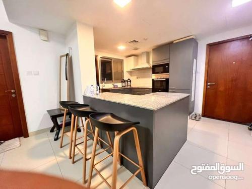 a kitchen with a counter and bar stools in it at One Bed Room Apartment Muscat Hills in Muscat