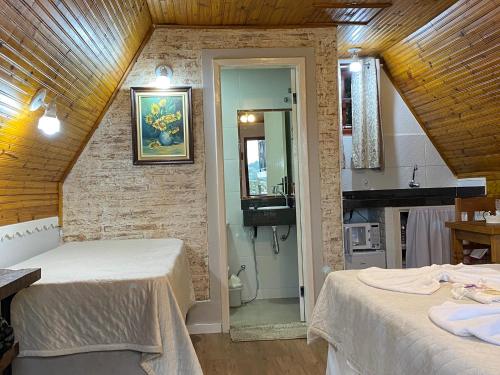 a bedroom with two beds and a bathroom with a sink at Chalés Paraíso Monte Verde in Monte Verde