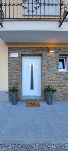 a white door on a brick building with two plants at Apartma Relax in Prestranek
