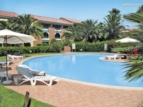 - une piscine avec des chaises et des parasols dans un complexe dans l'établissement Appartement de vacances Marine de Bravone - Corse, à Linguizzetta