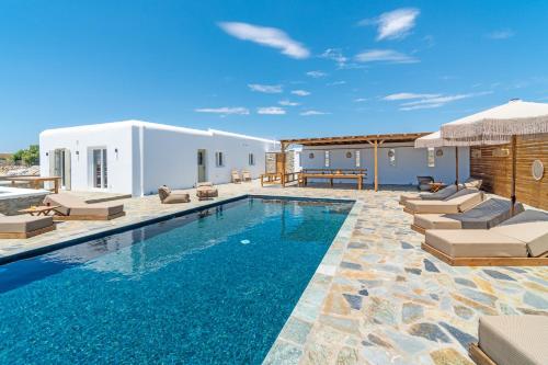 a swimming pool with lounge chairs and a villa at Le Ciel Suites & Villas in Mýkonos City