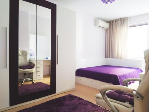 una camera da letto con specchio, letto e sedia di Modern apartment in Burgas a Burgas