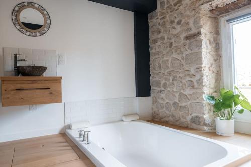 een badkamer met een bad en een stenen muur bij Ode au bonheur in La Cadière-dʼAzur