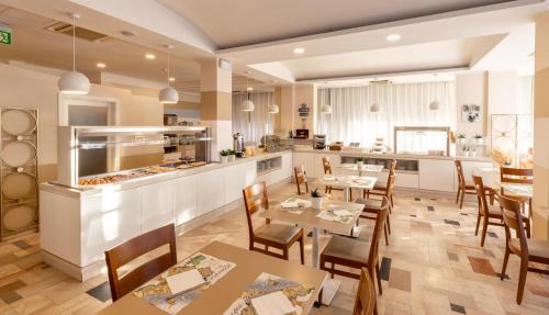 un restaurant avec des tables et des chaises et une cuisine dans l'établissement Hotel La Residenza, à Riccione