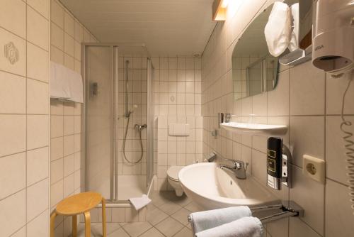 a bathroom with a sink and a shower and a toilet at Hotel-Restaurant Langen in Kattenes