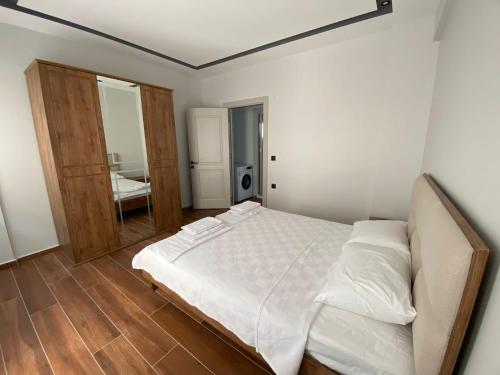 a bedroom with a white bed and a mirror at KARAASLAN GROUP TATİL EVLERİ in Kusadası