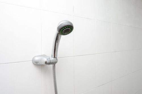 a shower with a shower head on a white tile wall at Urbanview Hotel Double Tree Purwokerto by RedDoorz in Purwokerto