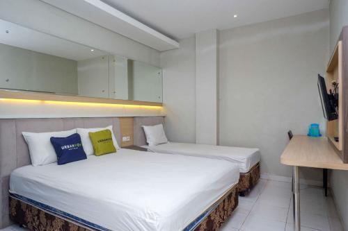 Cette petite chambre comprend deux lits et un bureau. dans l'établissement Urbanview Hotel Double Tree Purwokerto by RedDoorz, à Purwokerto