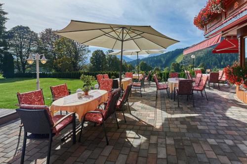a patio with tables and chairs and an umbrella at Landhaus Ramsau in Ramsau am Dachstein