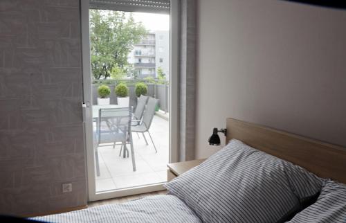 a bedroom with a bed and a balcony with a table at Apartament Amerigo in Wrocław
