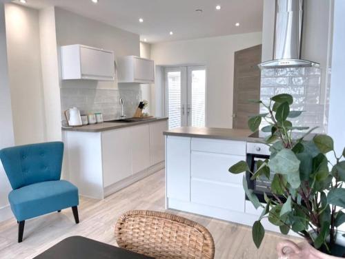 a kitchen with white cabinets and a blue chair at Lush Porthcawl Large Spacious 2 bedroom Apt, Garden, Prime Location in Porthcawl