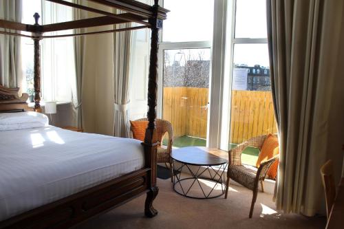 1 dormitorio con 1 cama, 2 sillas y ventana en The Woodhouse Hotel, en Largs