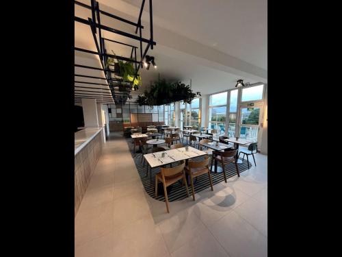 a dining room with tables and chairs and windows at Mercure Rouen Val de Reuil in Val de Reuil