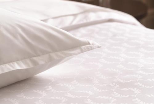 a white bed with white sheets and a pillow at Sheraton Grand Adana in Adana