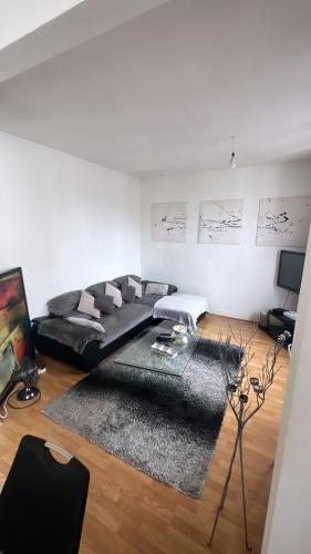 - un salon avec un canapé noir et un tapis dans l'établissement Appartement 60 m², porte de Saint-Cloud, à Boulogne-Billancourt