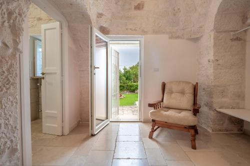 a room with a chair and an open door at Trullo Suite in Masseria in Cisternino