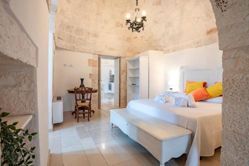 ein Schlafzimmer mit einem Bett und einer Bank in einem Zimmer in der Unterkunft Trullo Suite in Masseria in Cisternino