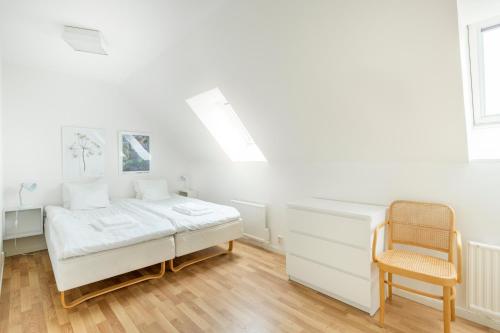 a white bedroom with a bed and a chair at Österlens Golfklubb - Lilla Vik in Simrishamn