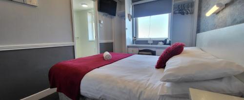 a bedroom with a bed with a red blanket and a window at The Blenheim Mount Hotel in Blackpool