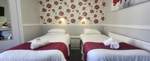 two beds in a room with white sheets and red blanket at The Blenheim Mount Hotel in Blackpool