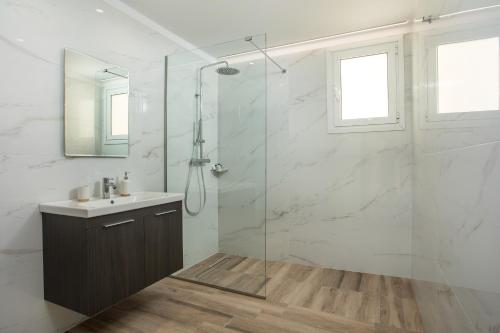y baño con lavabo y ducha acristalada. en Eden Lily- Luxurious Apartment with Sea View, en Rodas