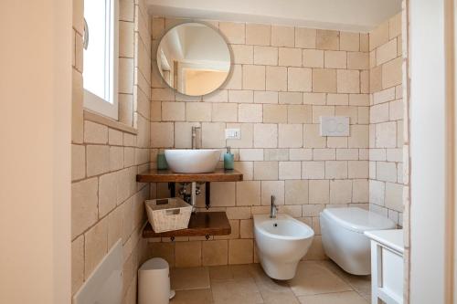 a bathroom with a sink and a toilet and a mirror at Trullo il Focolare in Masseria in Cisternino