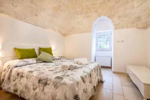 1 dormitorio con 1 cama grande y pared de piedra en Trullo il Focolare in Masseria, en Cisternino