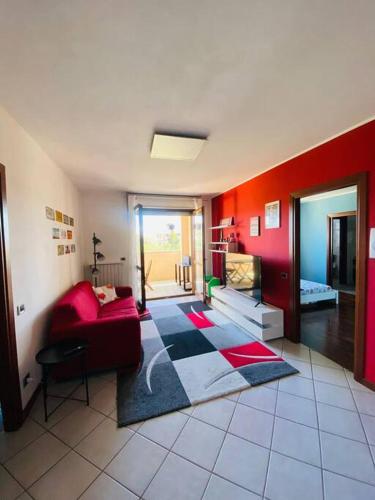 sala de estar con sofá y pared roja en intero Bilocale con terrazzo vicino a Milano, en Mairano