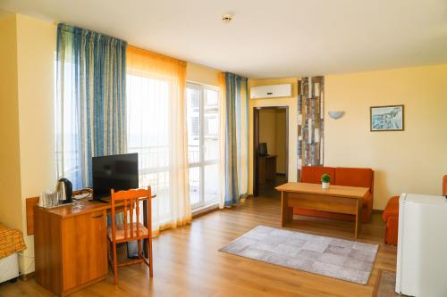 ein Wohnzimmer mit einem TV und ein Wohnzimmer mit einem Tisch in der Unterkunft Hotel Star in Sonnenstrand