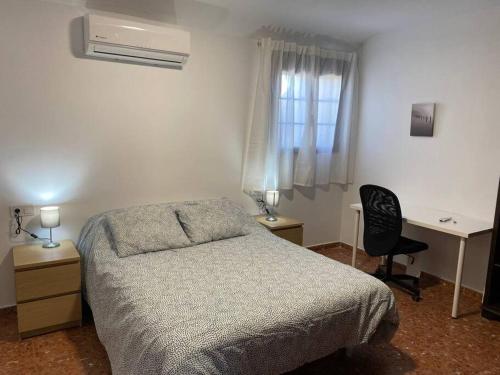 sypialnia z łóżkiem, biurkiem i oknem w obiekcie Piso grande de 120 m2, a 15' de la playa en coche w mieście Huelva