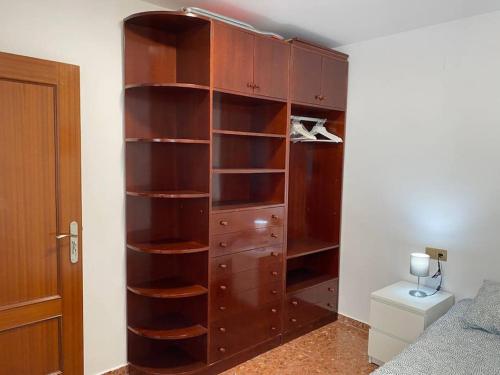 drewniana półka na książki w pokoju z łóżkiem w obiekcie Piso grande de 120 m2, a 15' de la playa en coche w mieście Huelva
