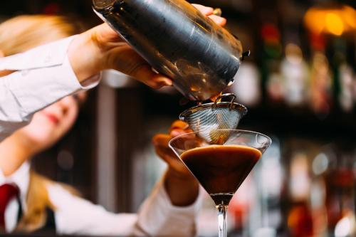 a person pouring a drink into a martini glass at Armagh City Hotel in Armagh
