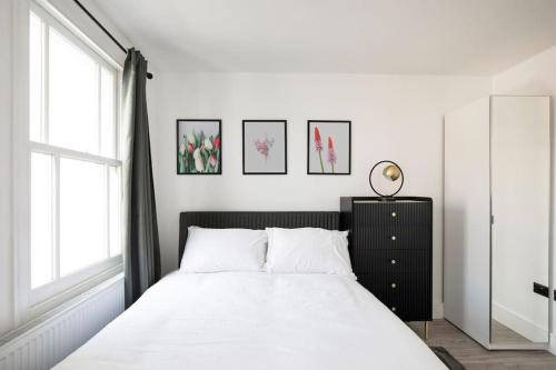 um quarto com uma cama com lençóis brancos e uma janela em Spacious Serenity in the Heart of Central London em Londres