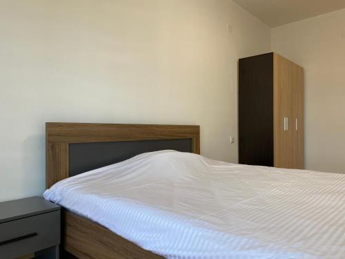 スコピエにあるS Apartmentの白いベッドと木製キャビネット付きのベッドルーム1室が備わります。