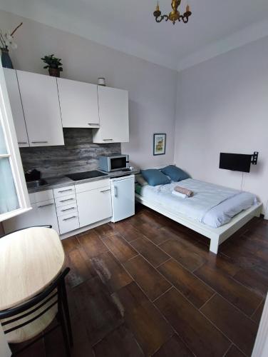 Cet appartement comprend une chambre avec un lit et une cuisine avec des placards blancs. dans l'établissement Appartement idéalement situé pour curiste, à Châtel-Guyon