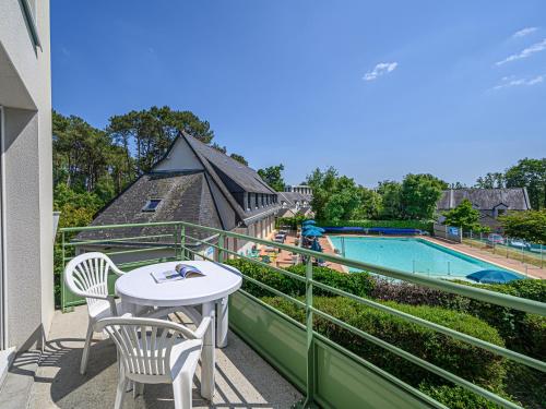 a balcony with a table and chairs and a pool at Vacancéole - Ker Goh Lenn - Vannes / Morbihan in Plescop