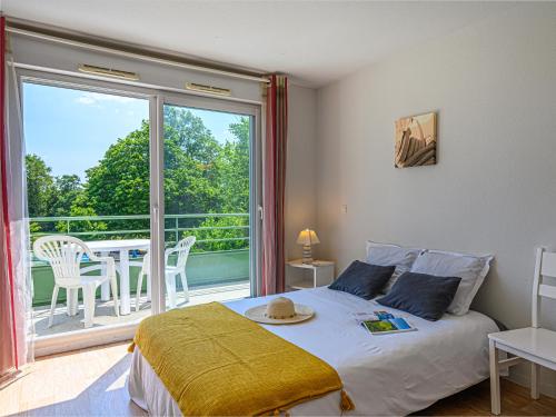 a bedroom with a bed and a balcony with a table at Vacancéole - Ker Goh Lenn - Vannes / Morbihan in Plescop