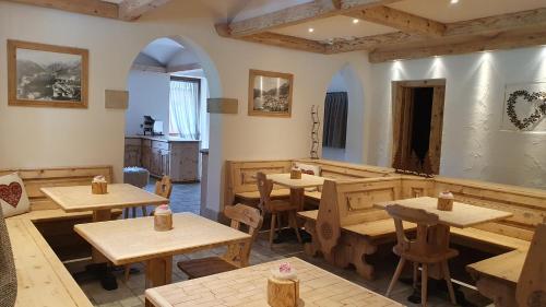 un restaurante con mesas de madera y sillas de madera en Albergo Meublè Victoria, en Auronzo di Cadore