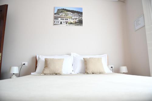 ein weißes Bett mit weißen Kissen im Schlafzimmer in der Unterkunft Guesthouse Leo in Berat