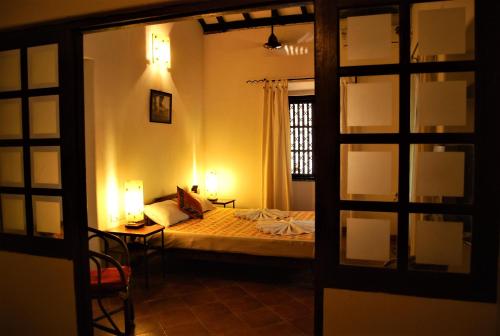 a bedroom with a bed and a table and a window at Granpa's Inn Hotel Bougainvillea in Anjuna