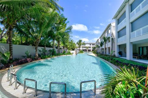 a swimming pool in front of a building with palm trees at Ki Residence in Grand Baie