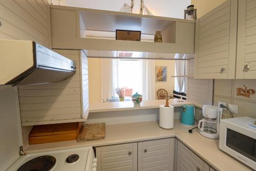 una cucina con armadi bianchi, lavandino e finestra di Beachfront Studio with Private Path to the Sea a Poros