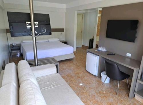 a hotel room with a bed and a couch and a television at Thermas diRoma c entrada Acqua Park in Caldas Novas